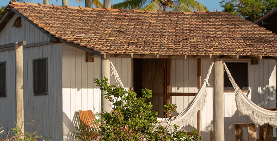 A cabana original de madeira, com redes na varanda